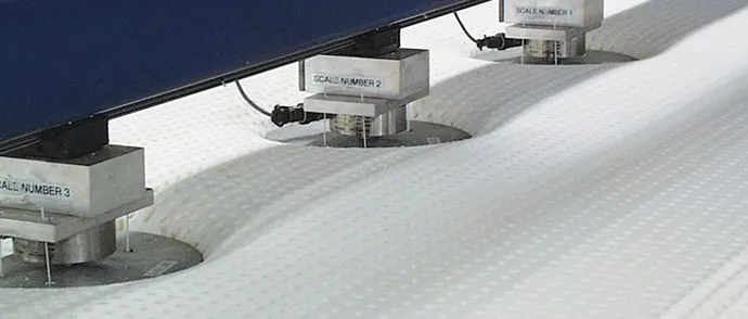Testopstelling met drie belaste meetstempels die een matras op meerdere punten indrukken